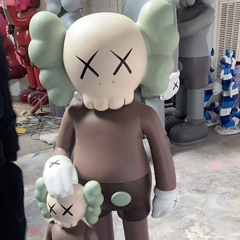 Two large KAWS-style figures on a concrete floor with people in the background.